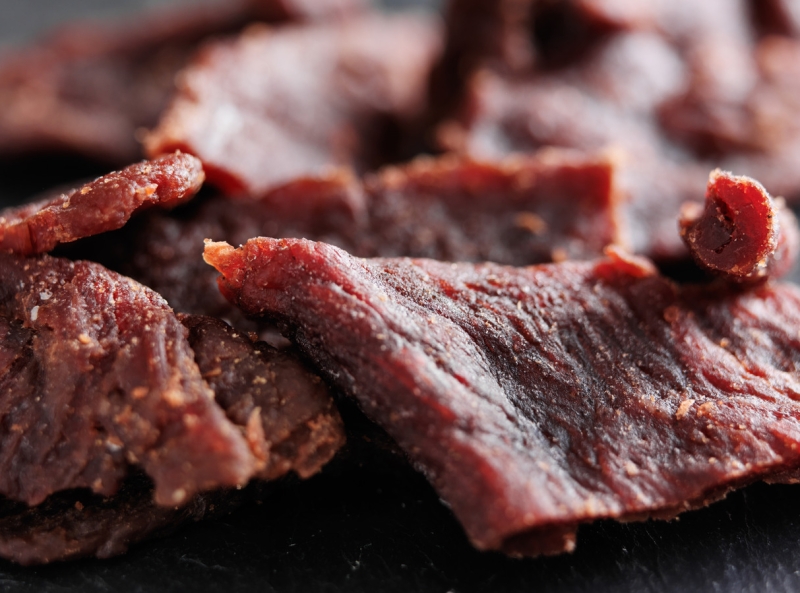 pile of beef jerky shot with selective focus on slate table